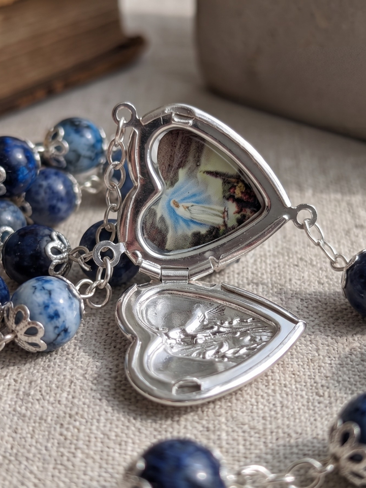 Heart-shaped locket with blue beads on a textured surface