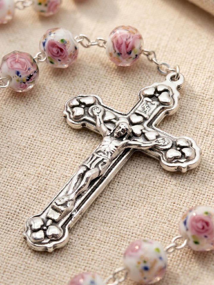Silver cross with floral beads on a textured fabric background