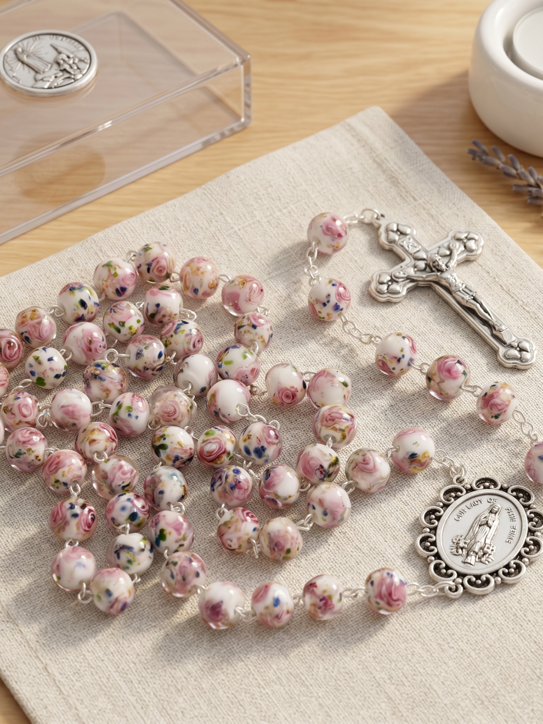 Pink rosary with floral designs on a beige cloth