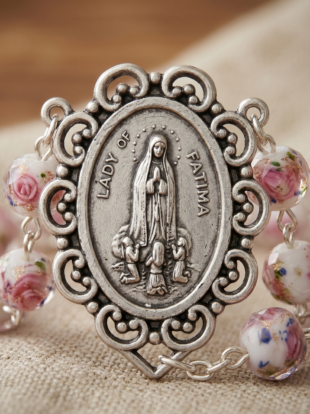 Silver religious pendant with 'Lady of Fatima' on a beige fabric background