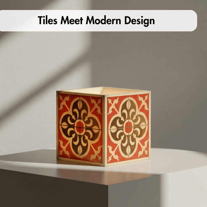 A decorative square box with a red, brown, and beige floral tile-inspired pattern sits on a white platform against a gray wall. A white banner at the top reads &