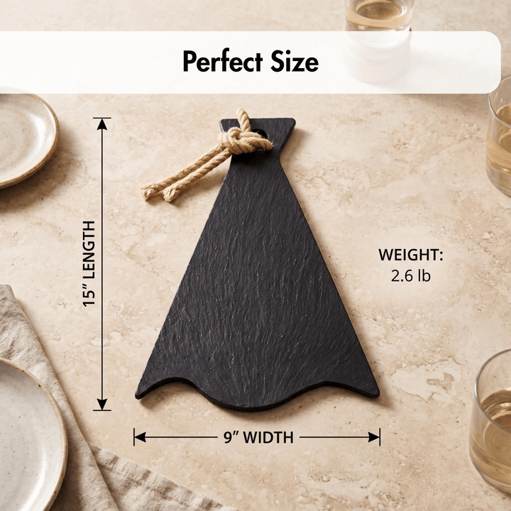 A black slate serving board shaped like a teardrop, shown on a beige stone surface with measurement callouts indicating 15-inch length, 9-inch width, and a weight of 2.6 lb.