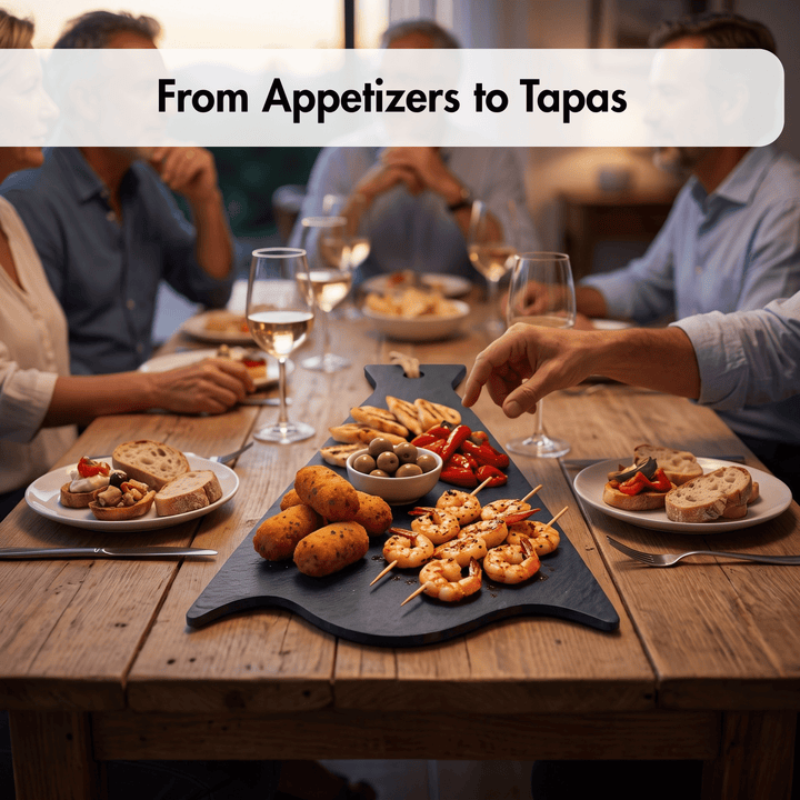 A dining table scene with a large black serving platter filled with appetizers and tapas, including shrimp skewers, potato balls, bread, olives, and sliced red peppers. Several people are seated around the table with wine glasses, and a banner at the top reads &