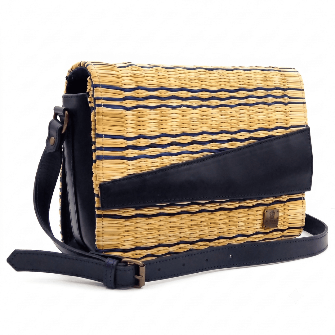 A woven straw crossbody bag with navy blue leather trim and a matching shoulder strap, set against a plain white background.
