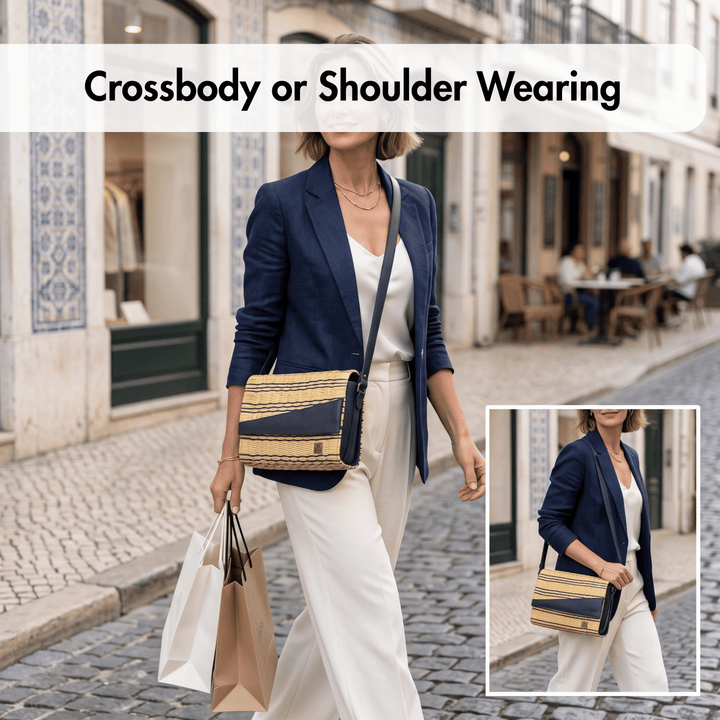 A woman wearing a navy blazer and white pants walks on a cobblestone street while carrying a navy and beige woven crossbody shoulder bag. The image includes a text overlay reading &