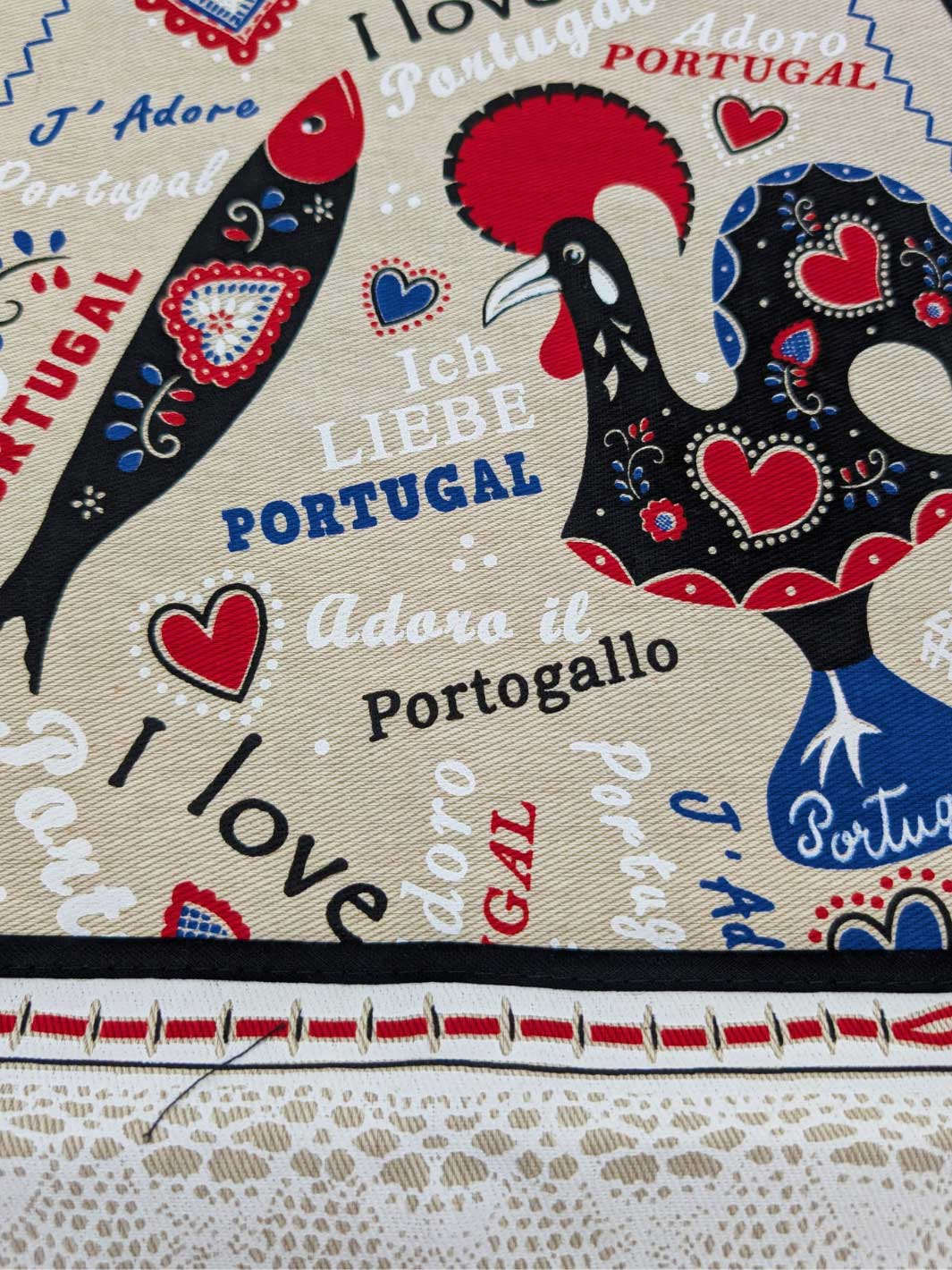 Decorative fabric with rooster design and text in multiple languages on a beige background