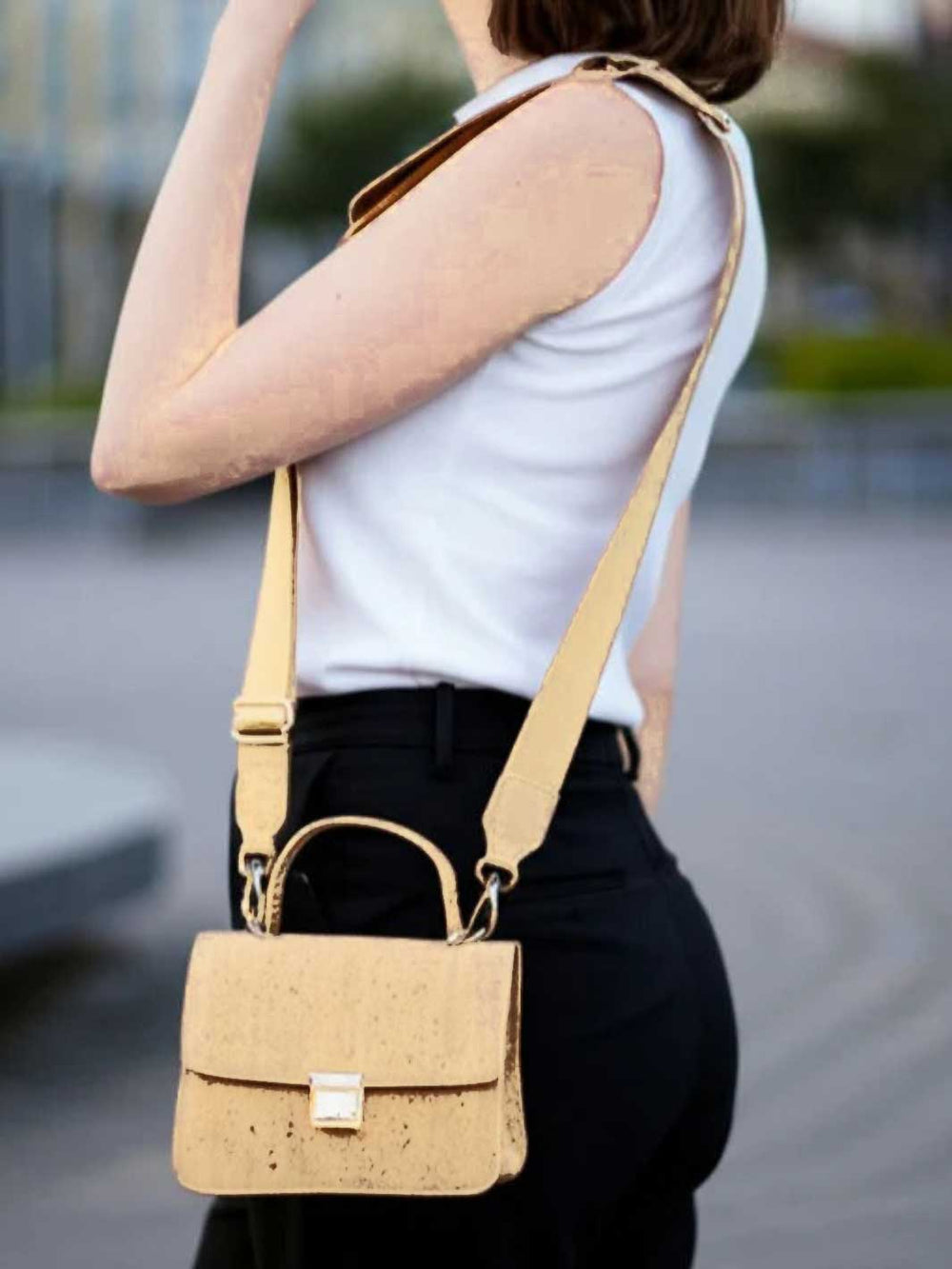 Person wearing a beige handbag with a blurred background
