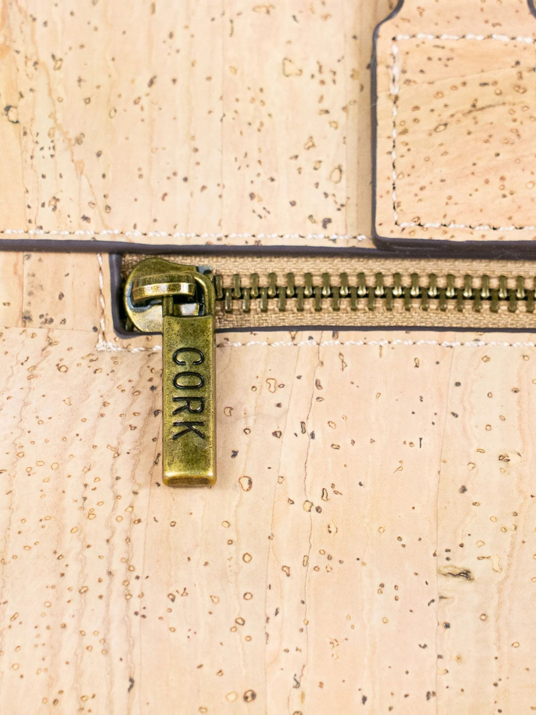 Close-up of a cork-textured surface with a gold zipper and 'Cork' label.