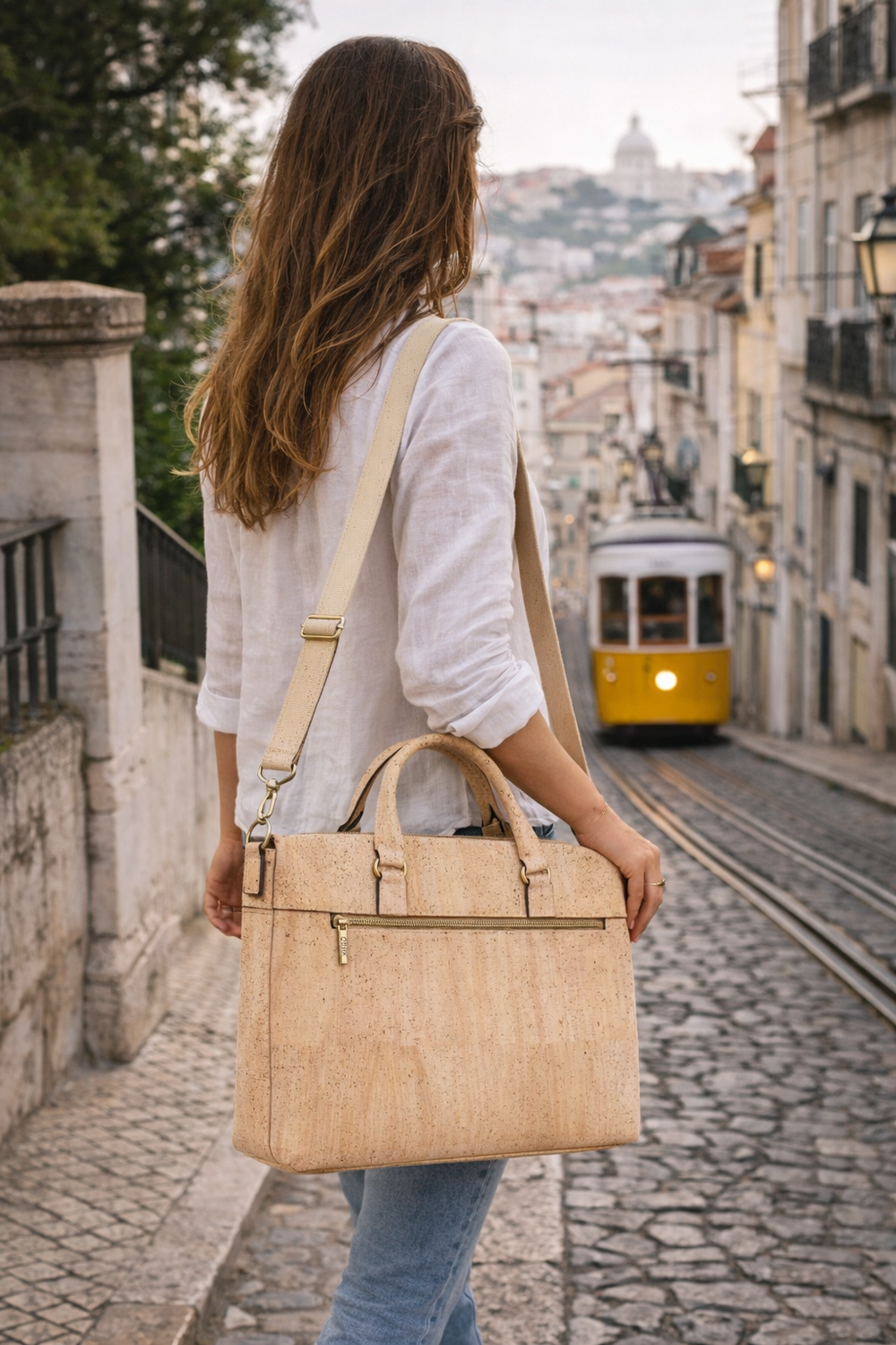 Woman holding a cork handbag on a street of Lisbon with a yellow tram in the background