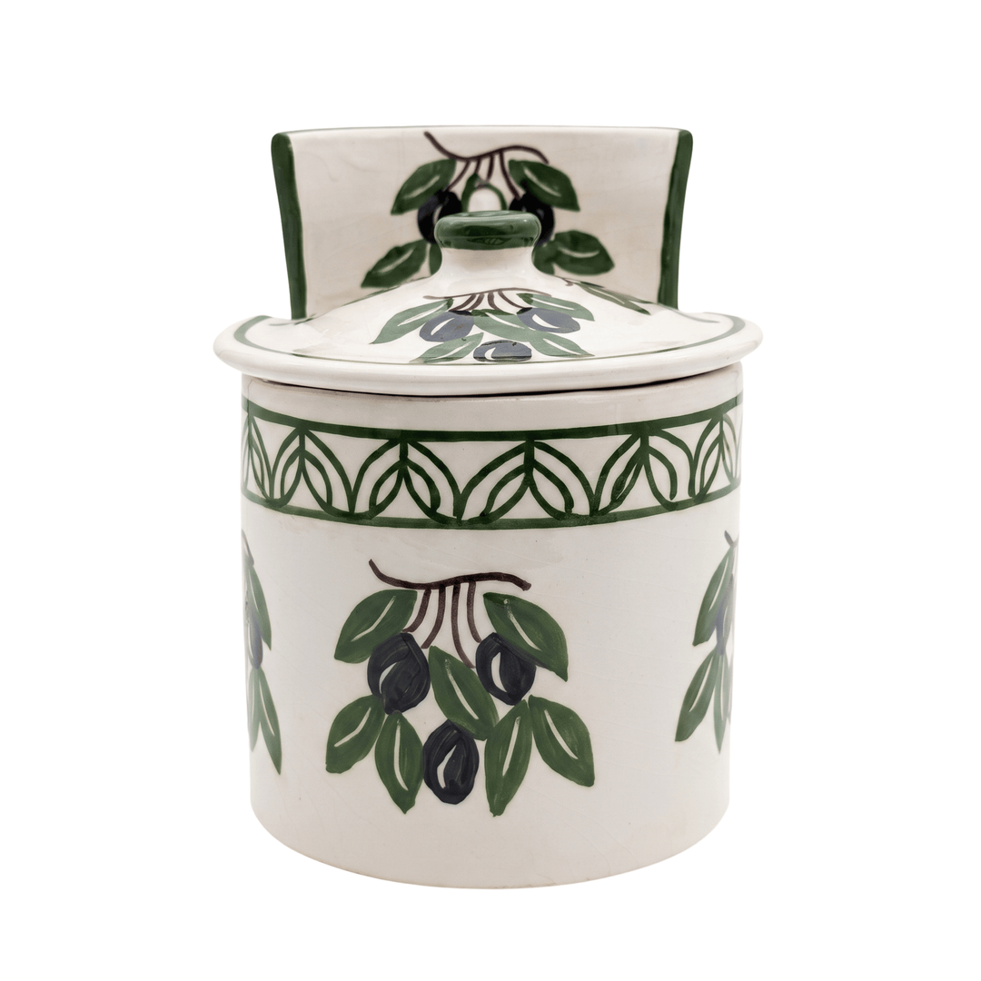 A white ceramic lidded jar decorated with green and black olive branch motifs, set against a plain white background.