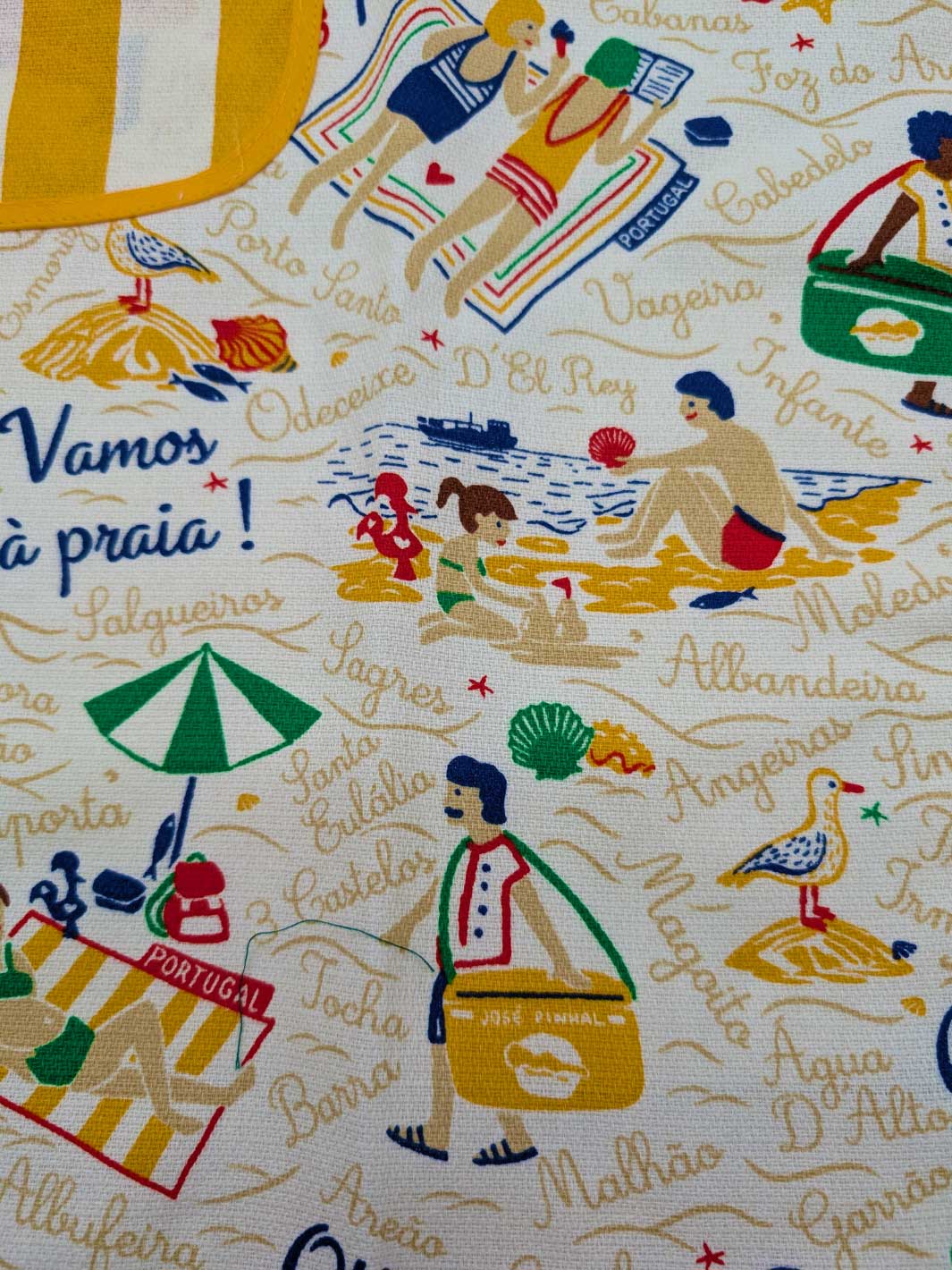 Fabric with beach-themed design featuring people at the beach and text.