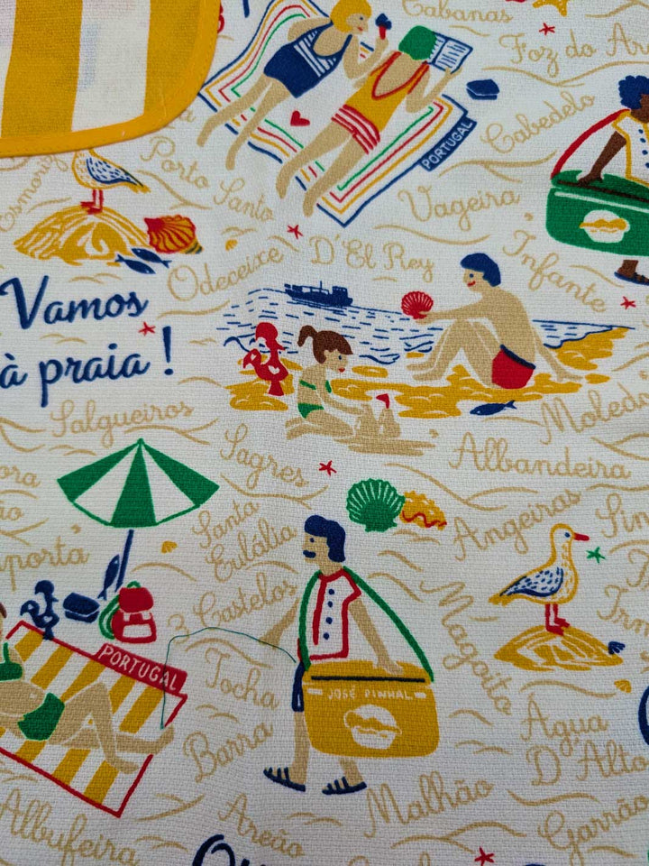 Fabric with beach-themed design featuring people at the beach and text.