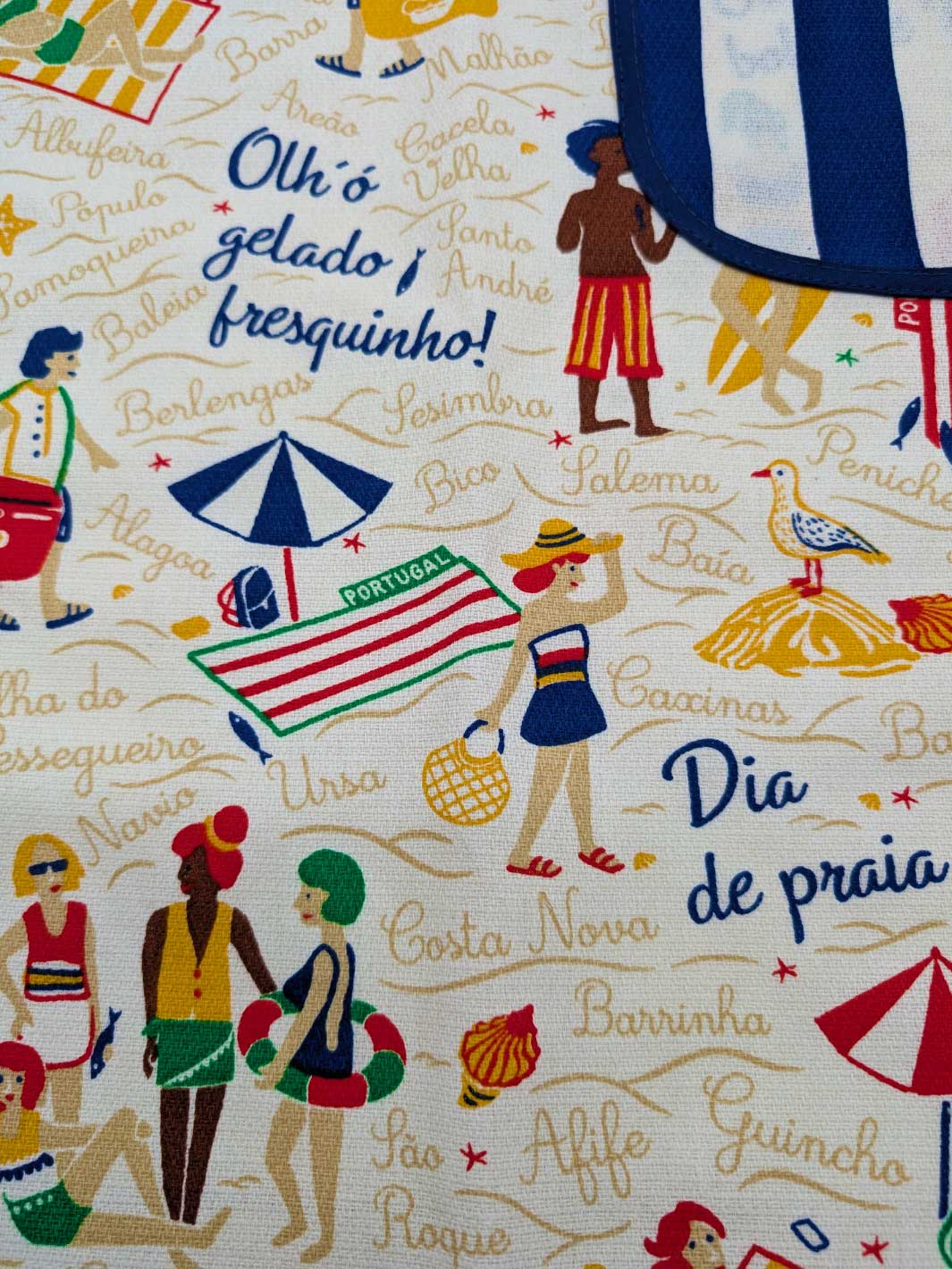Fabric with beach-themed design featuring people in swimsuits, umbrellas, and text on a white background.