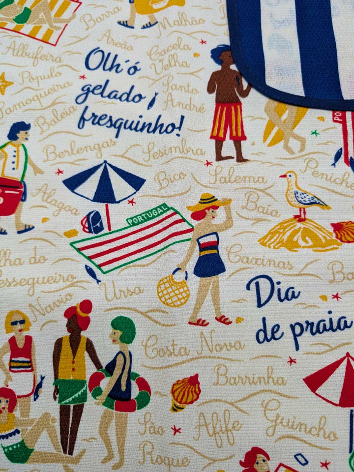 Fabric with beach-themed design featuring people in swimsuits, umbrellas, and text on a white background.