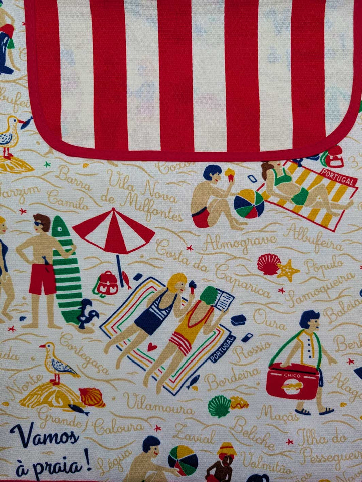 Fabric with beach-themed design featuring people, umbrellas, and text on a red and white striped background.