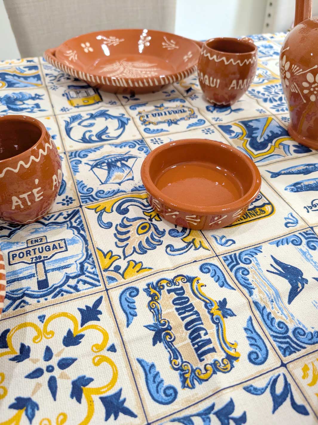 Ceramic bowls and cups on a table with Portuguese-themed tiles