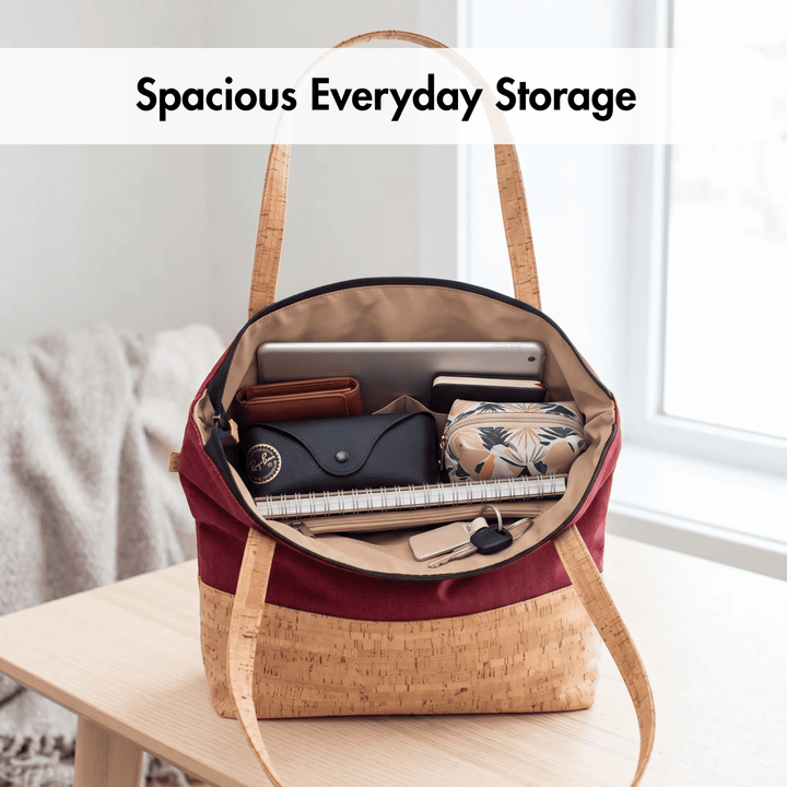 Red cork tote bag with handles on a wooden surface, containing items with text 'Spacious Everyday Storage'.