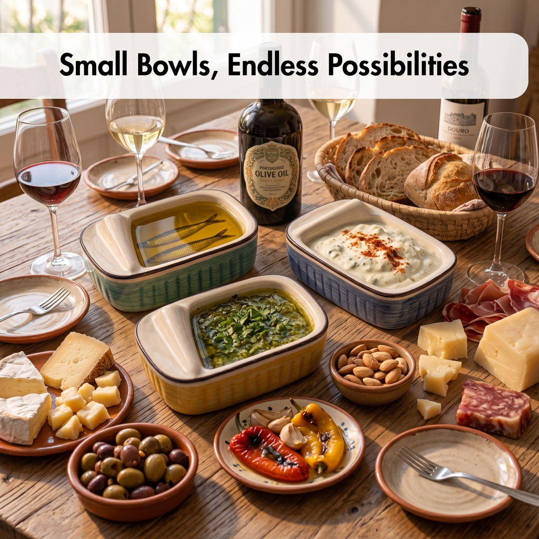 A styled tabletop spread of multiple small ceramic bowls and plates holding olive oil, a green salad, a white dip, bread, cheese, olives, nuts, cured meat, and wine glasses, with the text &