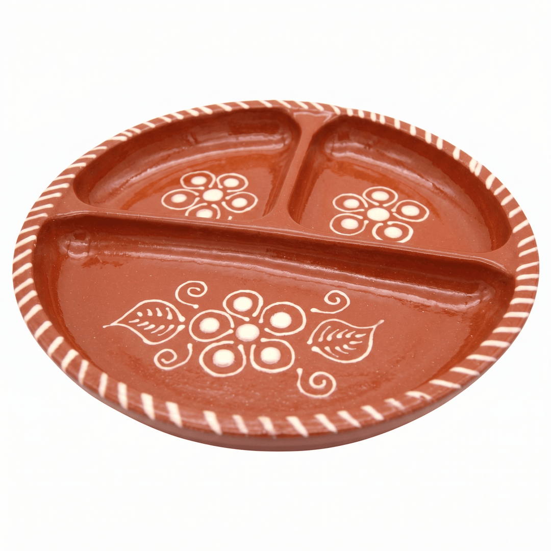 A terracotta-colored three-compartment ceramic plate with hand-painted white floral and leaf patterns and a striped rim, shown on a plain white background.