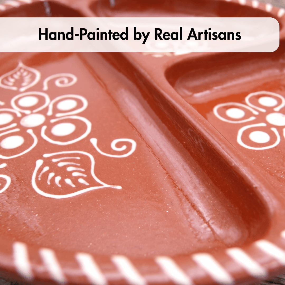 A close-up of a terracotta-colored ceramic plate with white hand-painted floral and leaf patterns, featuring a text banner at the top that reads &
