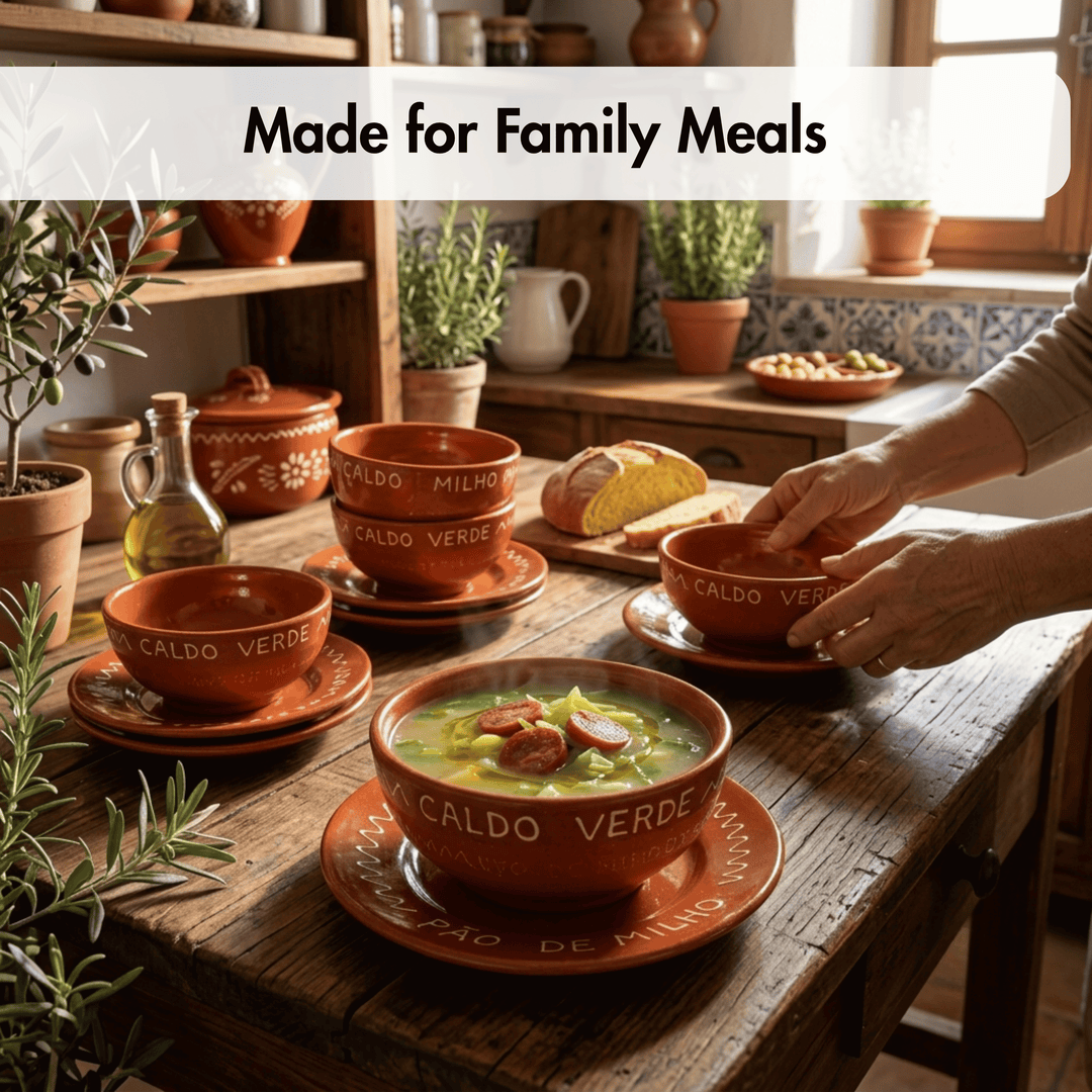 A rustic kitchen scene showing terracotta-colored ceramic bowls and matching saucers with white text, set on a wooden table with soup, bread, plants, and a person&