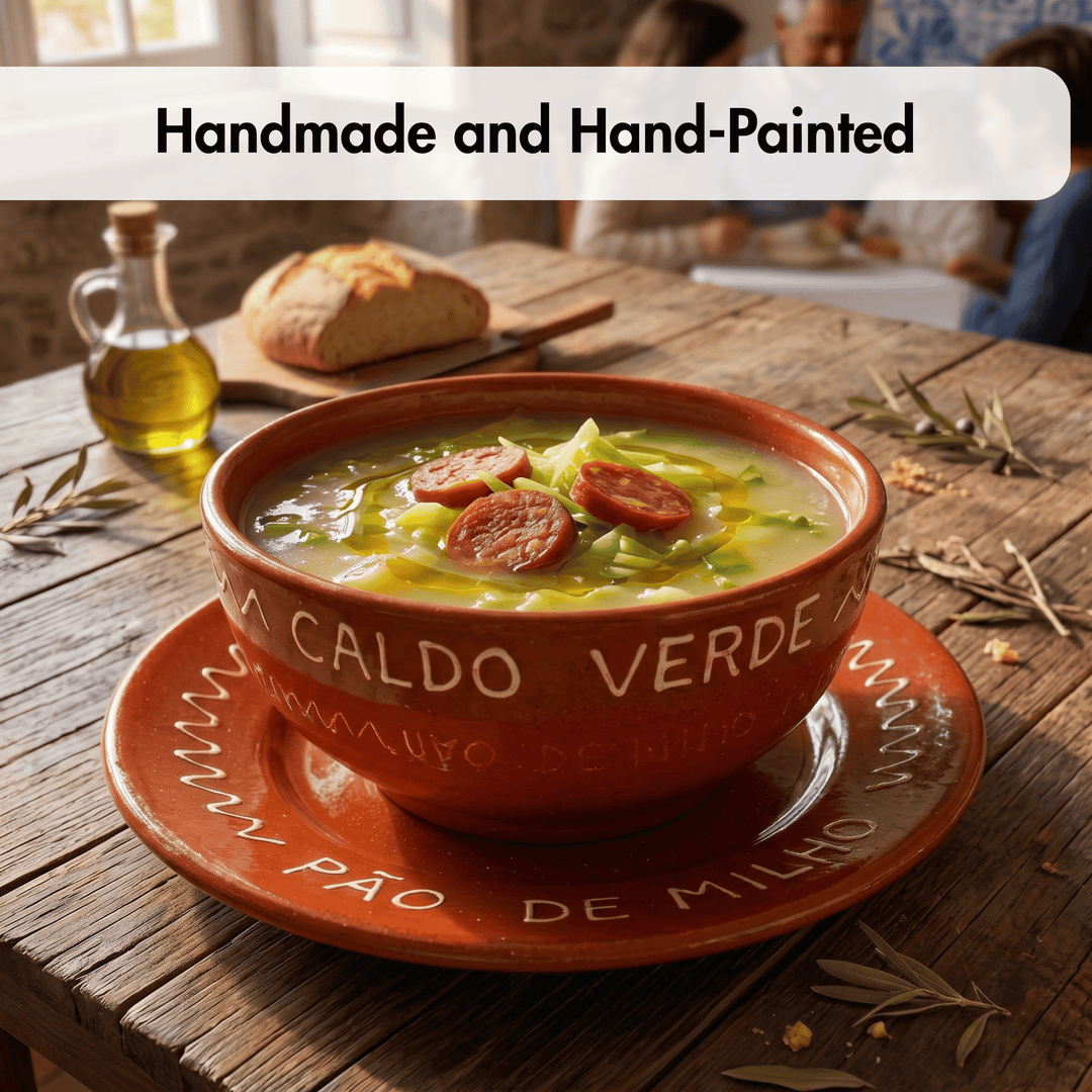 A rustic handmade terracotta bowl filled with green soup and sausage slices, set on a matching saucer on a wooden table. Bread, a bottle of olive oil, and dried herbs are visible in the background, with a text overlay at the top reading &