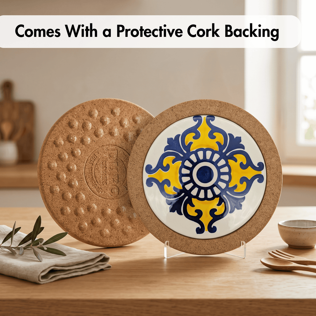 Two round cork coasters displayed on a wooden table. One coaster is shown from the back with a textured cork surface and debossed logo, and the other is shown from the front with a white center, blue and yellow ornamental tile pattern, and a cork border.