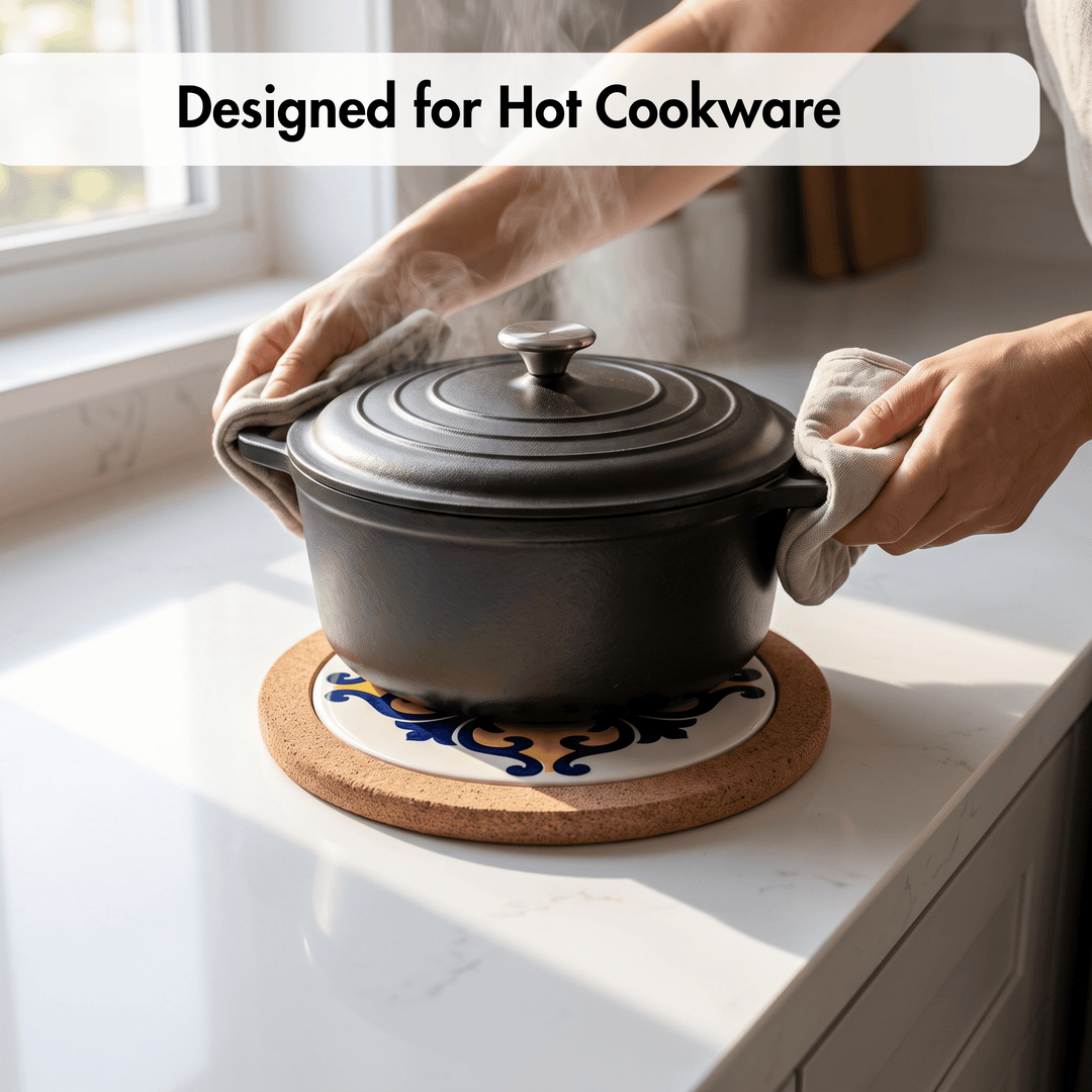 A black cast-iron Dutch oven pot with lid sits on a round cork trivet with a white ceramic center, on a white kitchen countertop. Hands wearing cloth oven mitts grip the pot handles, and steam rises from the pot.