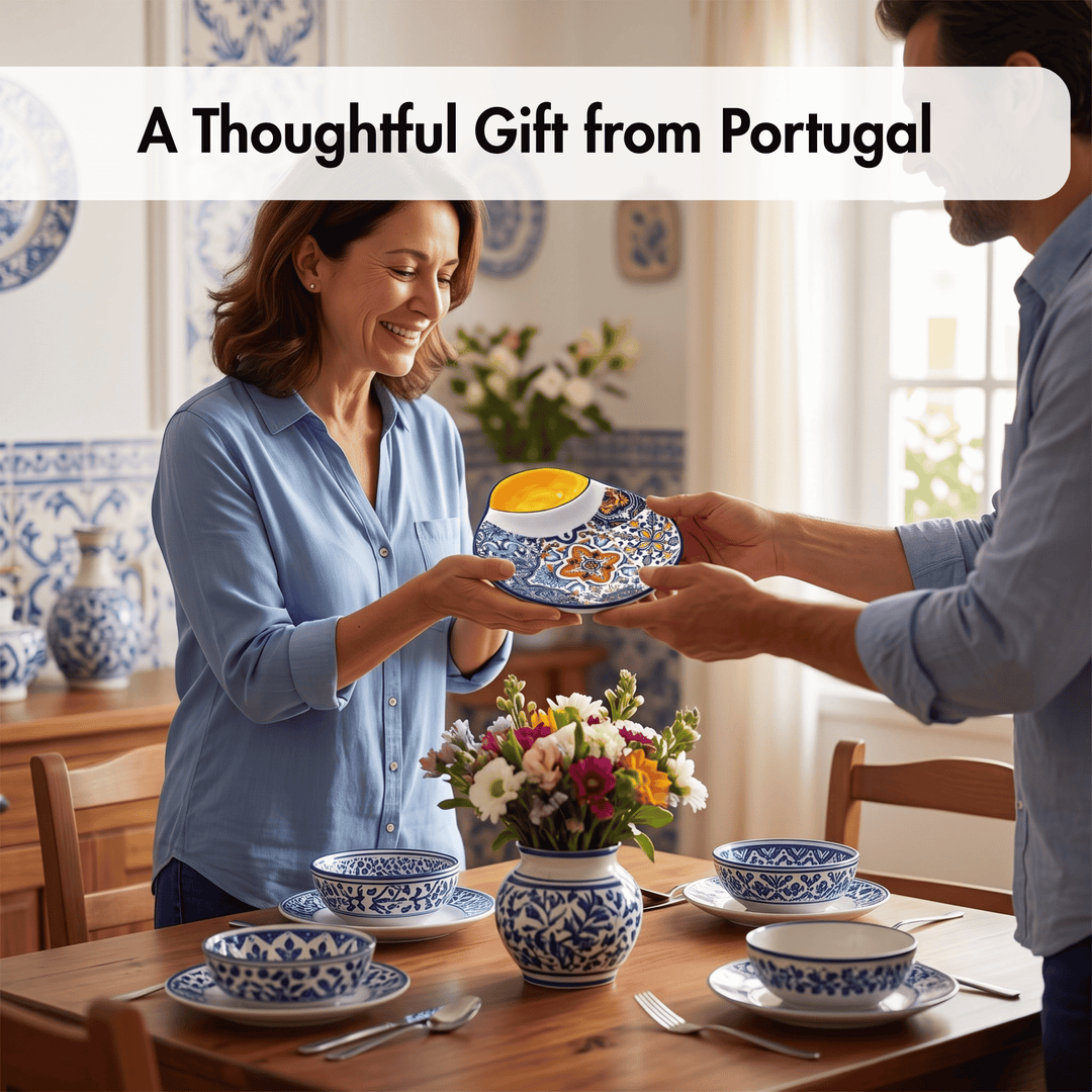 A man and a woman in a dining room exchange a blue and white patterned ceramic plate with a yellow bowl on top. The table is set with matching blue and white bowls, saucers, and cutlery, with a vase of flowers in the center.