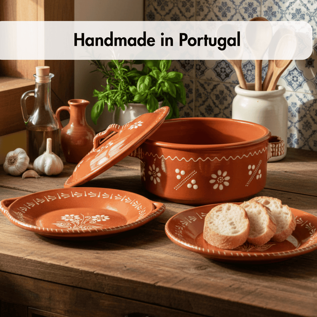 Handmade terracotta dishes with floral patterns on a wooden table, set against a rustic kitchen backdrop.
