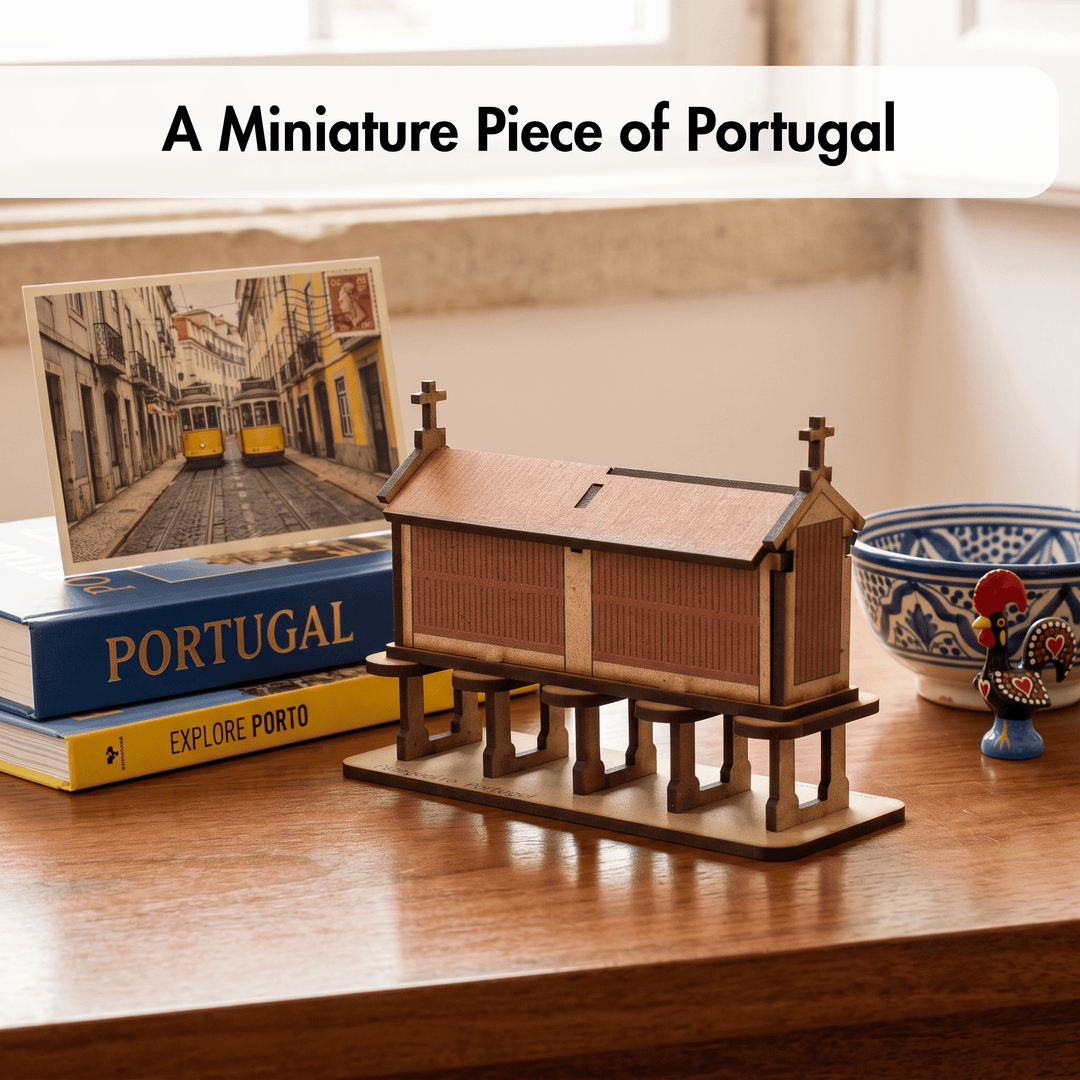 A miniature wooden model of a Portuguese church on a raised platform, displayed on a wooden table next to a book, a postcard, and a decorative bowl. A text banner at the top reads &