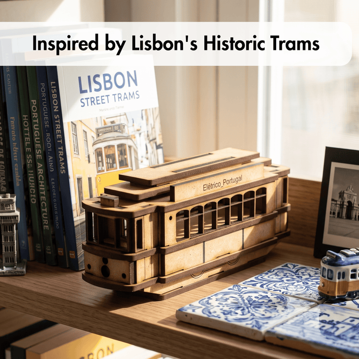 A wooden model of a Lisbon street tram displayed on a wooden shelf next to a book titled &