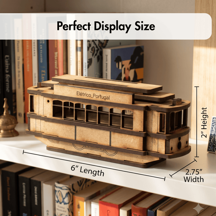A wooden model of an Eléctrico de Portugal cable car displayed on a bookshelf, with overlaid dimension lines showing 6 inches length, 2 inches height, and 2.75 inches width, plus the text &