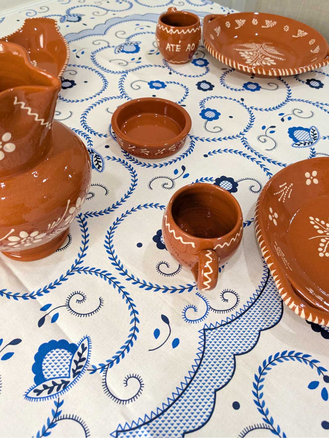 Clay pottery items on a tablecloth with blue and white patterns