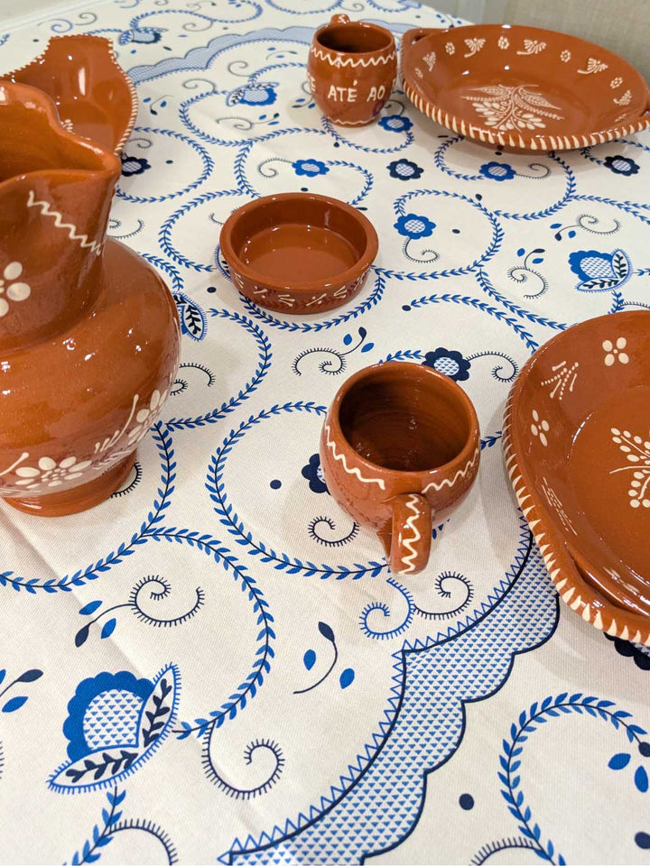 Clay pottery items on a tablecloth with blue and white patterns