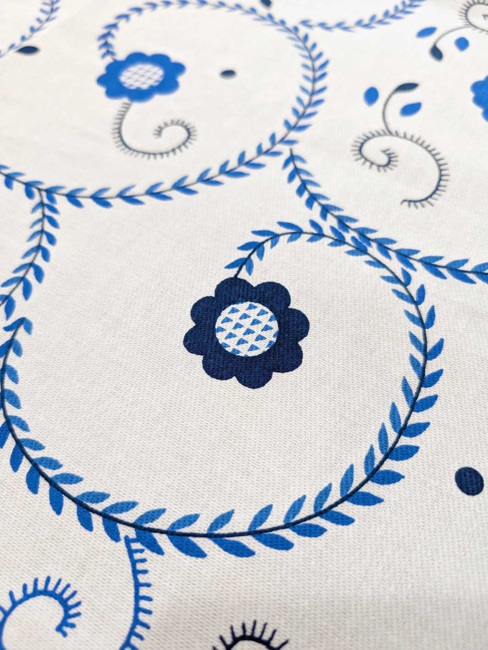 Close-up of blue floral and leaf patterns on a white fabric background