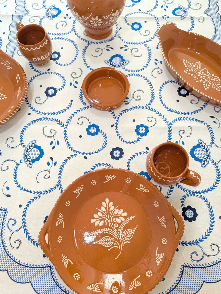 Ceramic dishes with decorative patterns on a tablecloth with blue floral designs.