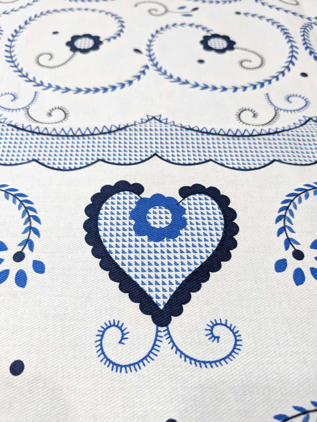 Close-up of a decorative fabric with blue heart and floral patterns on a white background