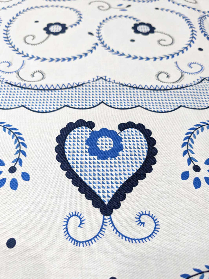 Close-up of a decorative fabric with blue heart and floral patterns on a white background