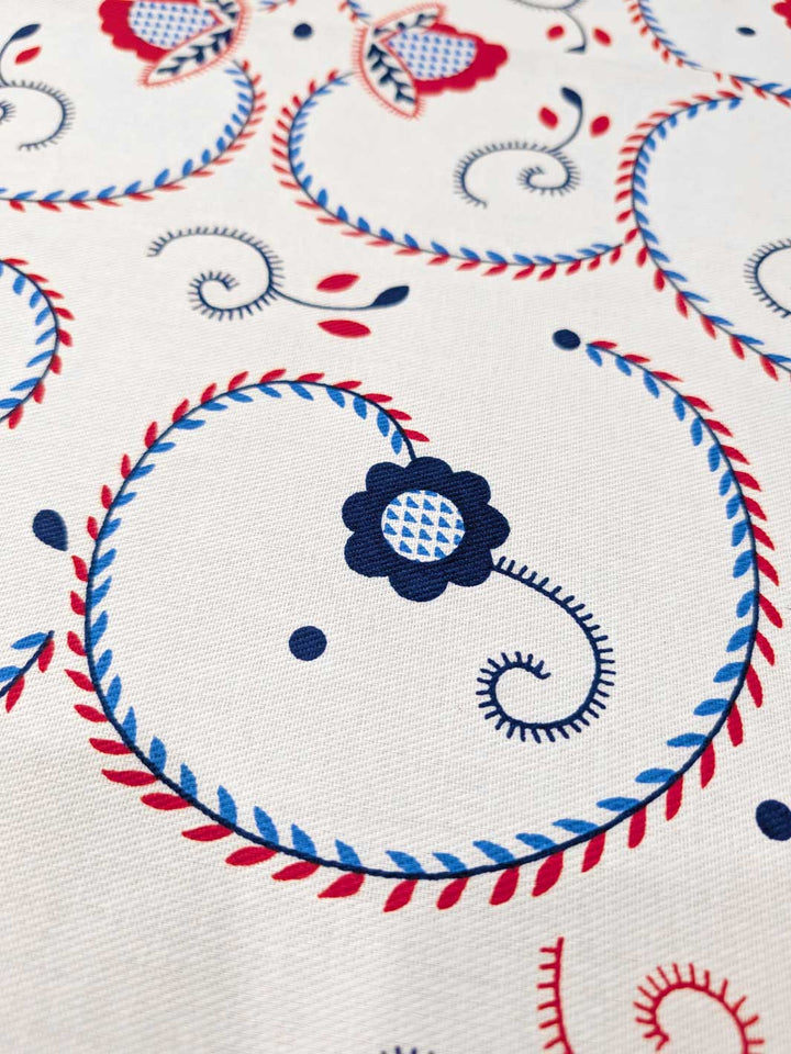 Decorative fabric pattern with blue flowers and red and blue swirls on a white background