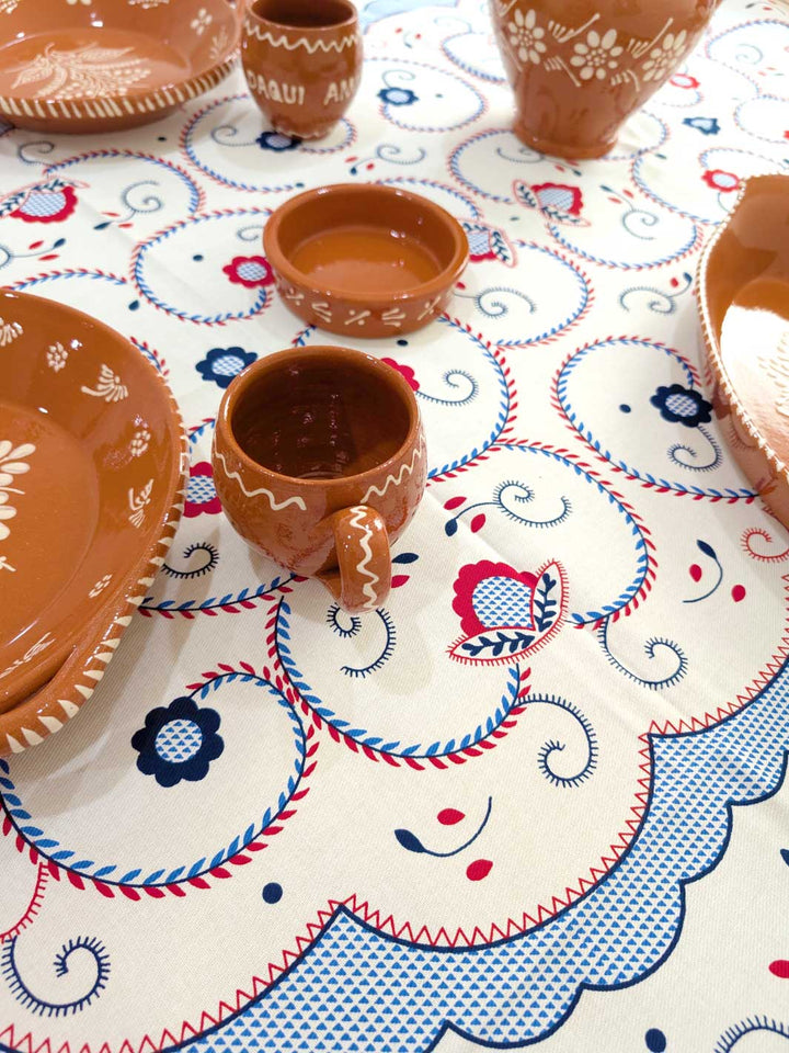 Ceramic cups and bowls on a decorative tablecloth with floral patterns