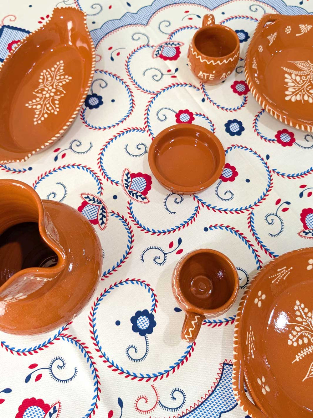 Ceramic dishes with decorative patterns on a tablecloth with intricate designs.