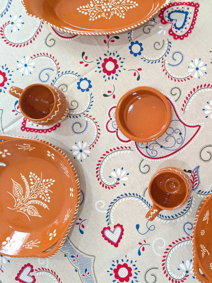 Ceramic plates and cups with floral patterns on a decorative tablecloth.