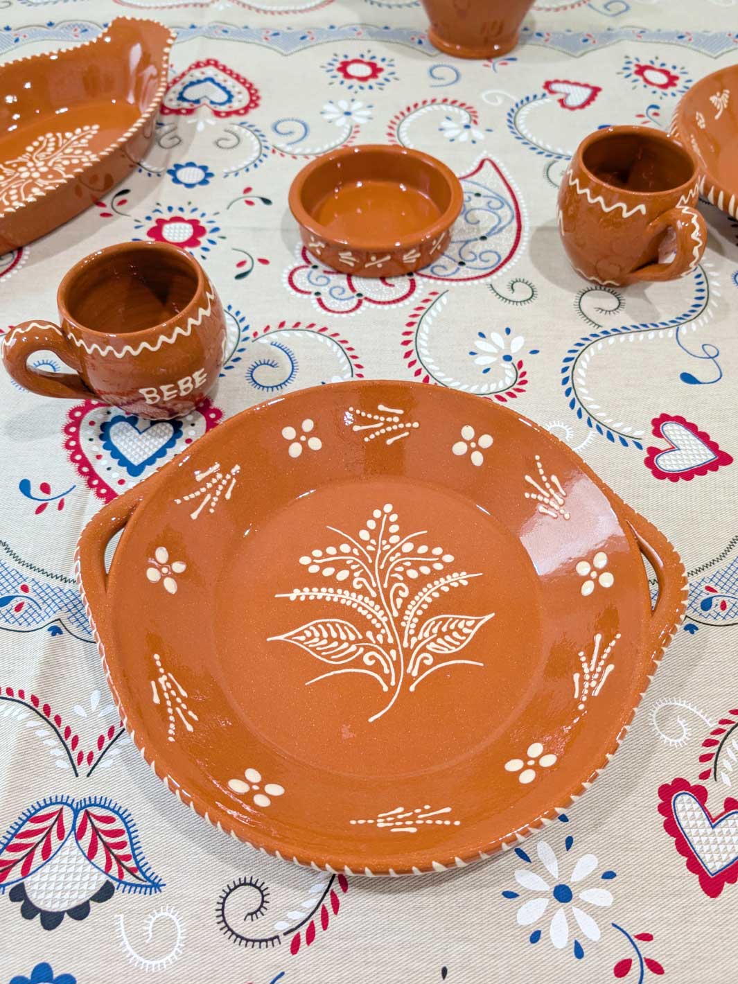 Ceramic plates and cups with floral patterns on a colorful tablecloth