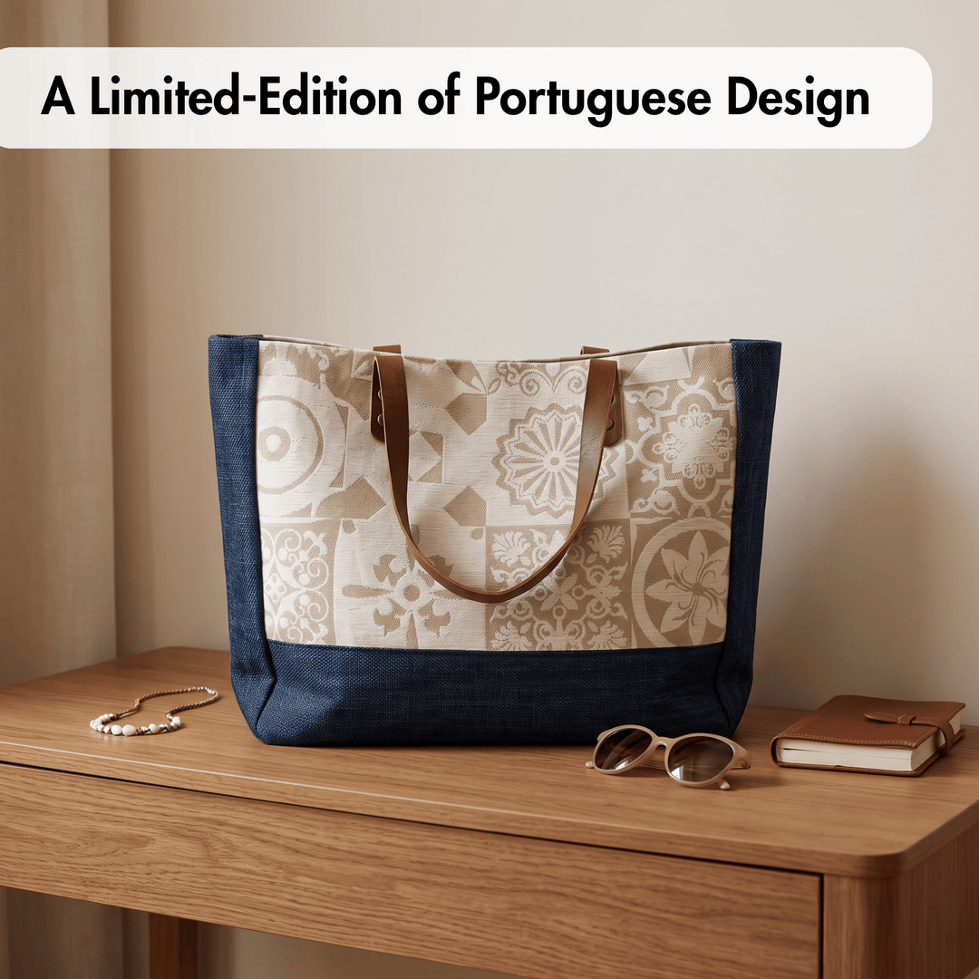 A tote bag with a navy blue base and sides, and a central panel featuring a beige and cream Portuguese-style tile pattern, displayed on a wooden table with sunglasses, a book, and a necklace.